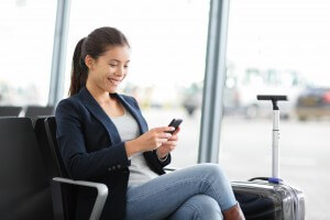 Airport business woman on smart phone at gate waiting in termina